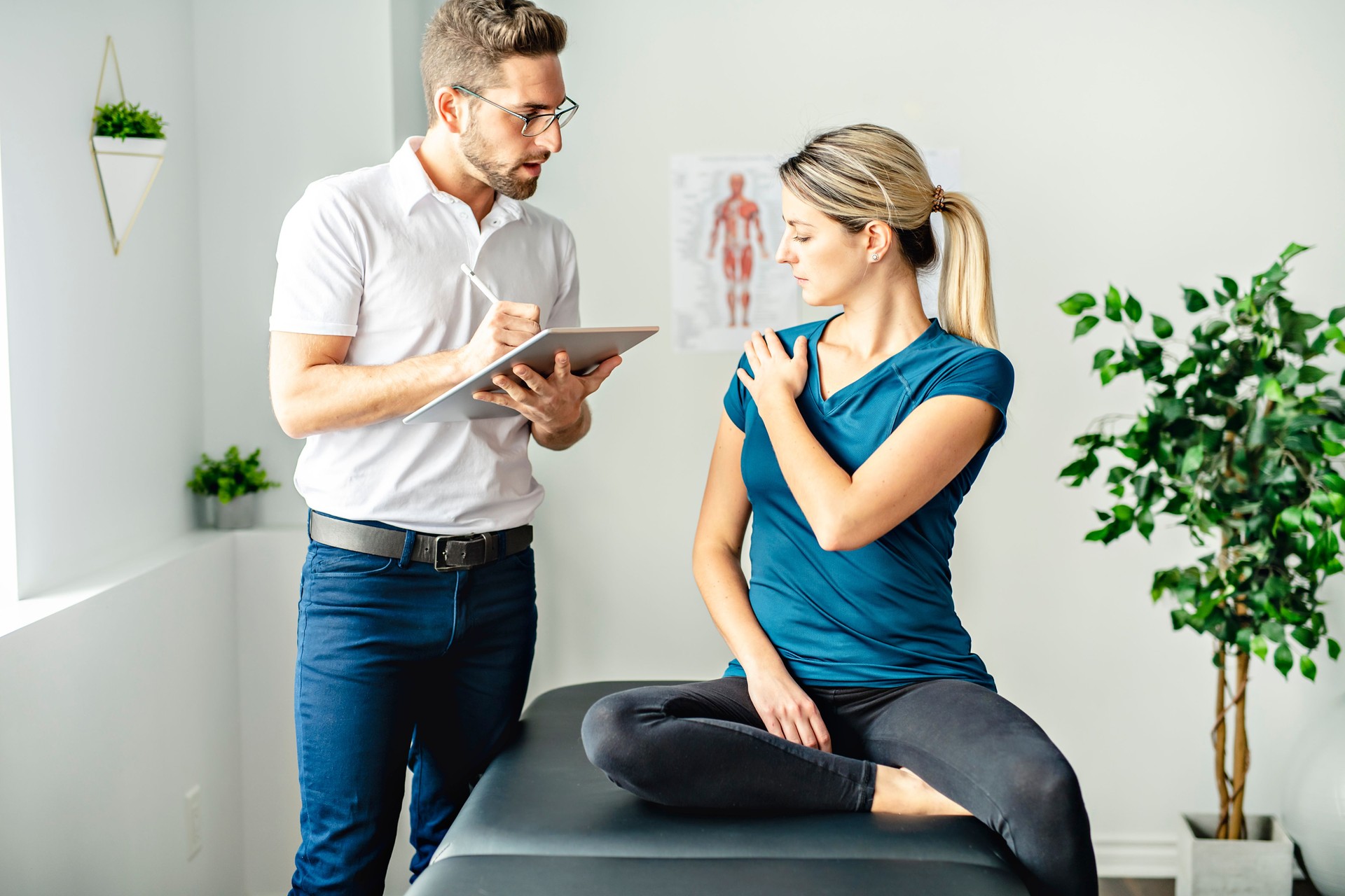 A Modern rehabilitation physiotherapy man at work with woman client talk about shoulder problem